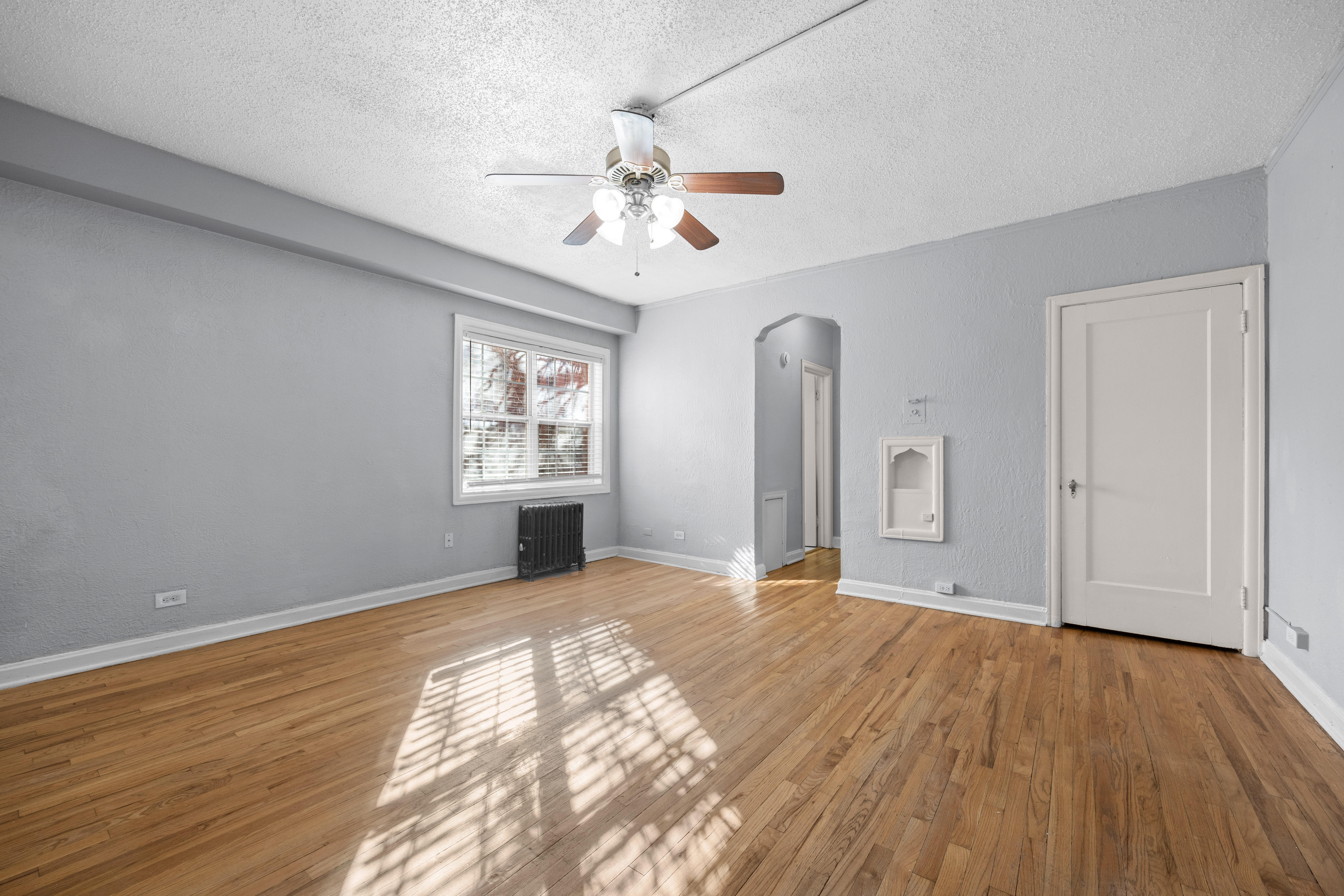 A room with a ceiling fan and wooden floors.